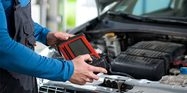 Mechanic using an automotive diagnostic scan tool to read engine codes